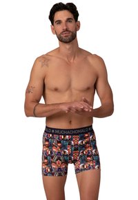 Színes boxernadrág, testhezálló kialakítással, elasztikus anyagból készült. Tengerészkék derékpántja van, rajta a "MUCHACHOMALO" logóval és élénk, többféle mintázattal.