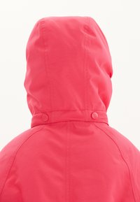 Vaaleanpunainen hupparitakki, jossa on sileä pinta, kaksi pyöreää nappia kauluksessa ja saumatonta muotoilua, joka sopii ulkokäyttöön.