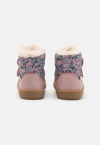 Bottines roses avec dessus en textile à motifs floraux, doublure en fausse fourrure et deux sangles réglables. Semelle en caoutchouc avec détail de grip texturé.