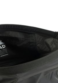 Zwarte stoffen tas interieur met een gladde textuur, voorzien van een merklogo en gedrukte tekst. Subtiel ruitpatroon zichtbaar op de voering.