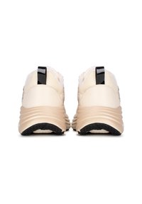Zapatillas deportivas beige con textura suave, paneles de malla y acento negro en el talón. Suela de goma curva con superficie antideslizante.