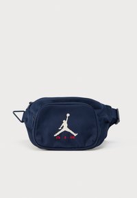 Τσαντάκι μέσης σε ναυτικό μπλε ύφασμα με φερμουάρ, διακοσμημένο με λευκό λογότυπο Jumpman και κόκκινο κείμενο "AIR" στο μπροστινό μέρος. Περιλαμβάνεται ρυθμιζόμενο ιμάντας.
