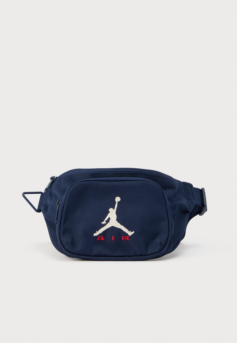 Τσαντάκι μέσης σε ναυτικό μπλε ύφασμα με φερμουάρ, διακοσμημένο με λευκό λογότυπο Jumpman και κόκκινο κείμενο "AIR" στο μπροστινό μέρος. Περιλαμβάνεται ρυθμιζόμενο ιμάντας.