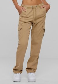 Khaki cargo kalhoty s elastickým pasem, šňůrkovým zapínáním, bočními kapsami a tapered střihem. Materiál je lehký a hladký.