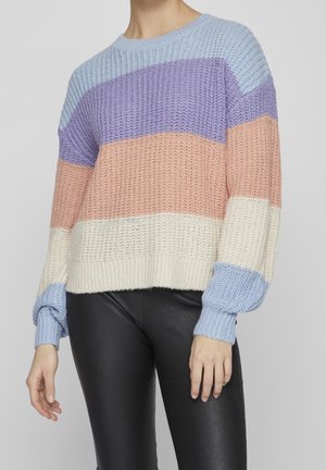 Personne portant un pull en tricot avec des rayures horizontales bleu clair, lavande, pêche, crème et bleu clair, associé à un pantalon noir.