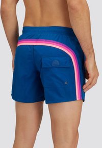 Pantaloni da bagno blu con strisce diagonali rosa e viola, vita elastica e una tasca laterale con etichetta del logo.