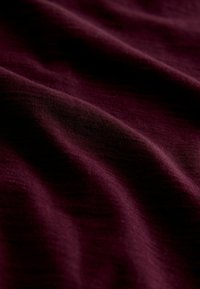 Bordo tkanina s mekanom, glatkom teksturom i s nježnim nabranim detaljima te laganim sjajem, pogodna za razne tekstilne primjene.