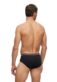 Schwarze Slips aus glattem Stoff; mit einem kontrastierenden weißen Streifen am Bund; ergonomisch gestaltet für eine optimale Passform.