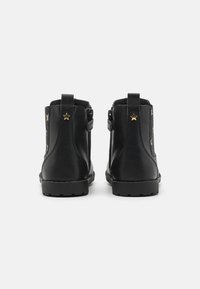 Bottes en cuir noir à hauteur de cheville avec une finition lisse, présentant un accent en étoile, des côtés texturés et une semelle en caoutchouc durable.