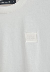 Vit bomull t-shirt med rund halsringning och en fyrkantig broderad "POLO CLUB"-logotyp på framsidan, som visar en mjuk och slät textur.