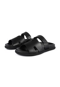 Sandali in pelle nera con design aperto sulla punta, due cinturini regolabili e suola in gomma testurizzata. Presentano dettagli traforati per la traspirabilità.