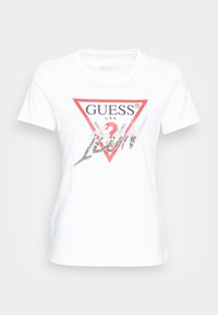 Hvid bomulds t-shirt med en rød trekantet grafik med "GUESS" og en sølvglitrende inskription, rund hals, kortærmet.