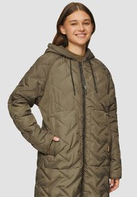 Lange olijfgroene pufferjack met een capuchon, gewatteerde textuur, ritssluiting aan de voorkant en zijzakken. Beschikt over verstelbare koorden bij de capuchon.