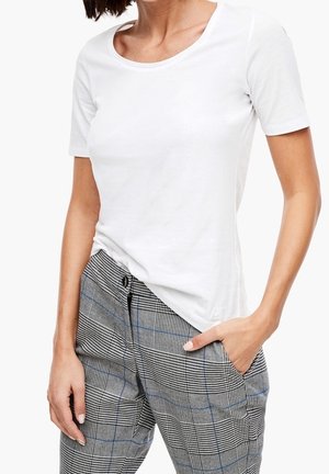 Biała koszulka z krótkim rękawem i zaokrąglonym dekoltem, w połączeniu z szarymi spodniami w kratę z czarnymi i niebieskimi wzorami.