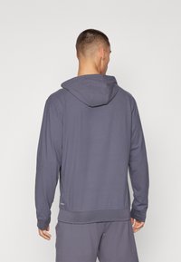 Kapuzensweatshirt in dunkelgrau, aus glattem Stoff gefertigt. Verfügt über lange Ärmel, eine lässige Passform und ein dezentes Logo nahe dem Saum.