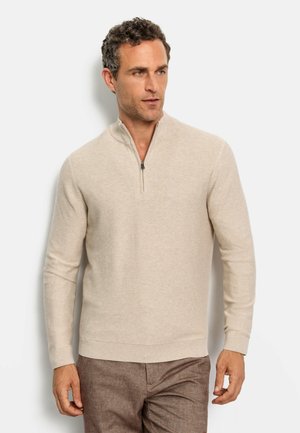Beige trui met een kwart rits kraag, geribbeld textuur en lange mouwen, met subtiele horizontale strepen. Aangesloten pasvorm.