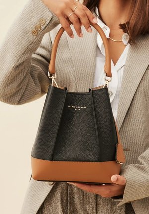 Schwarze Leder-Eimer-Tasche mit einem sandfarbenen Boden, strukturierter Form, Obergriff und goldener Markenprägung. Verfügt über eine strukturierte Oberfläche und Metallbeschläge.