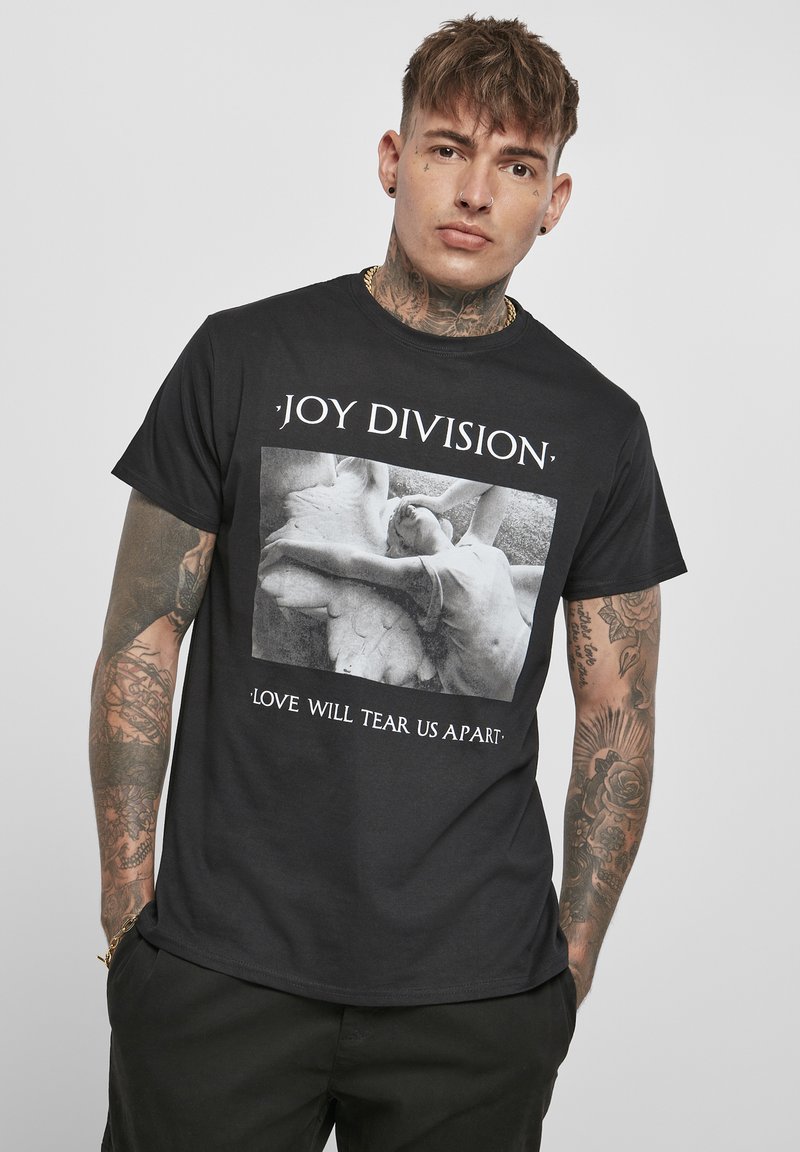 T-shirt en coton noir avec un graphisme sur le devant représentant une image en noir et blanc de deux silhouettes, accompagnée du texte "JOY DIVISION" et "LOVE WILL TEAR US APART."