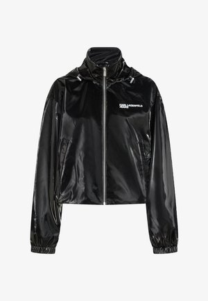 Črna sijoča jakna z zadrgo, visokim ovratnikom, elastičnimi manšetami, stranskimi žepi in logotipom "KARL LAGERFELD JEANS" na levi strani prsnega koša.