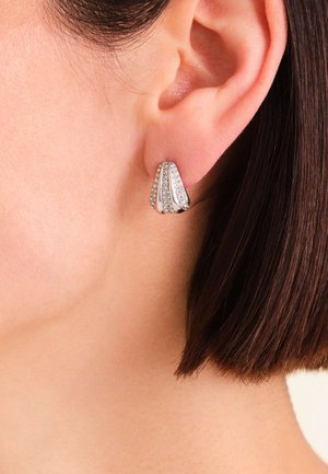 Orecchini tono argento con un design a coste e piccole pietre trasparenti incastonate, dal look elegante e moderno.