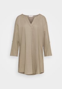 Beige tuniek met een V-hals, driekwartmouwen en een subtiele textuur. Heeft een loose fit en een licht gebogen zoom.
