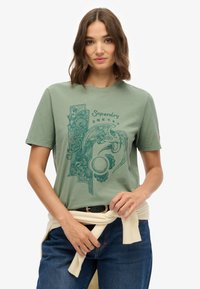 Groen katoenen T-shirt met een gedetailleerd blauw grafisch ontwerp met bloem- en vogelmotieven. Korte mouwen, ronde hals, relaxte pasvorm.