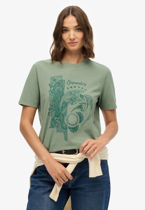 Grünes Baumwoll-T-Shirt mit einem detaillierten blauen Grafikdesign mit Blumen- und Vogelmuster. Kurze Ärmel, Rundhalsausschnitt, lockere Passform.