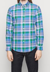 Košile s dlouhým rukávem na knoflíky v modro-zeleno-růžovém károvaném vzoru. Má límec s knoflíky a zakřivený lem. Vyrobena z látky s hladkou texturou.