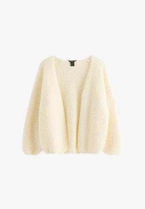 Kermanvärinen, avoimella edustalla oleva pörröinen neuletakki, jossa pitkät ilmapallohiha ja rento istuvuus.