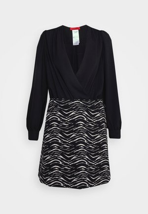 Schwarzes Kleid mit langen Ärmeln und tiefem V-Ausschnitt. Der Rock zeigt ein schwarz-weißes Wellenmuster. Hergestellt aus einem glatten Stoff.