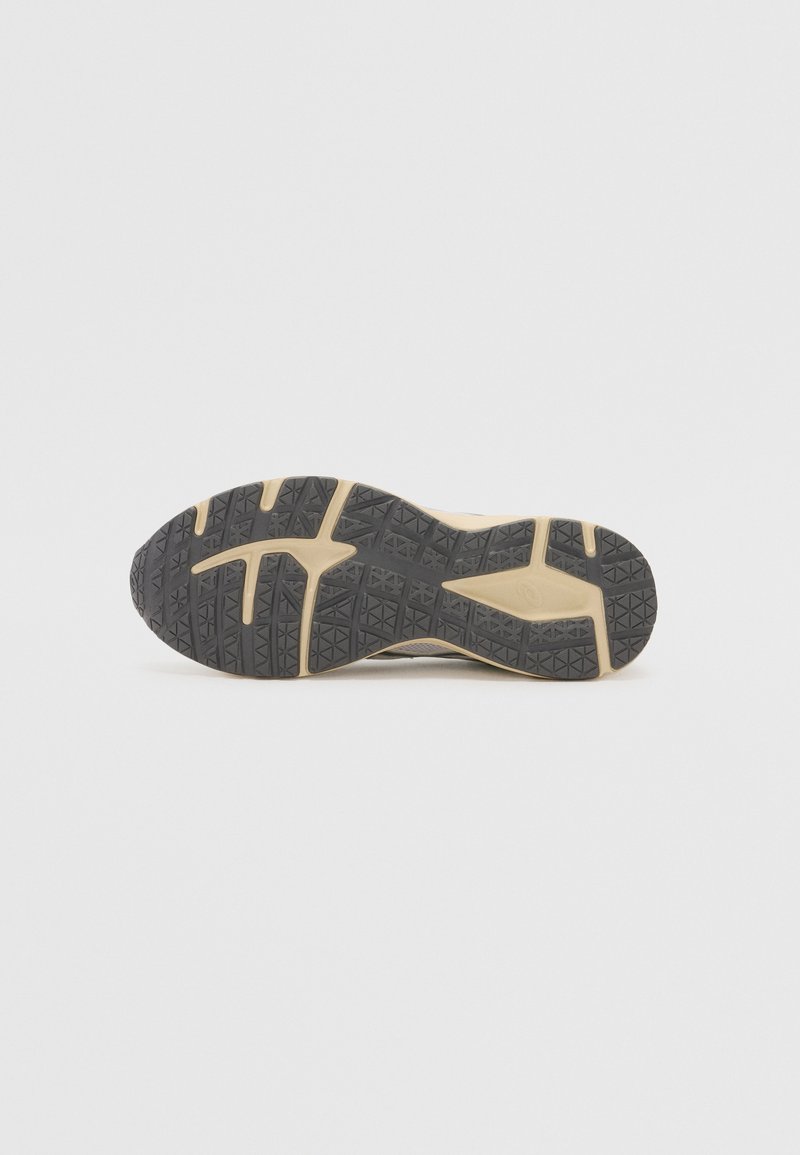 Suela de zapatilla para correr que presenta goma negra con un patrón de agarre texturizado, incluyendo líneas y formas prominentes para tracción.