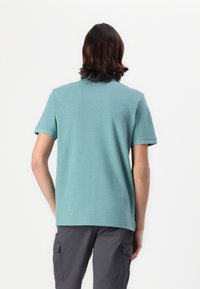 Teal kortærmet polo-shirt lavet af blød bomuld. Har rund hals og en afslappet pasform. Ingen synlige mønstre eller accenter.
