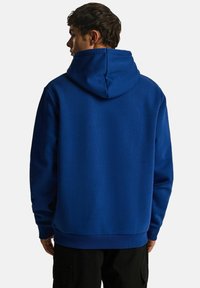 Niebieska bluza z kapturem o teksturowanym wykończeniu, z prążkowanymi mankietami i dolnym końcem. Posiada podwójny design kieszeni z przodu.