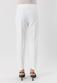 Pantaloni bianchi su misura con una texture liscia, design a gamba dritta e dettagli con pieghe. Presentano una vita con passanti per cintura e una lunghezza cropped.