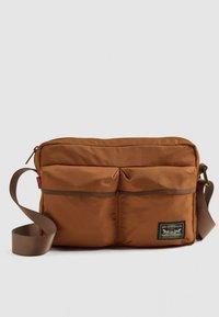 Borsa a tracolla marrone con due tasche frontali, tracolla regolabile e toppa con il logo Levi Strauss & Co. su sfondo bianco.