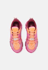 Une paire de baskets à lacets rose et orange avec des semelles épaisses, vue de dessus sur un fond blanc uni.