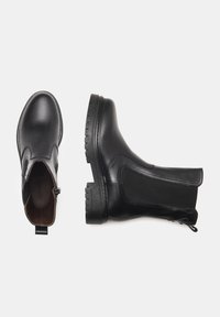 Bottes ankle en cuir noir avec panneaux latéraux élastiques, bout rond et semelle en caoutchouc texturé. Caractéristiques d'une languette pour un enfilage et un retrait faciles.