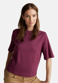 T-shirt a maniche corte, girocollo, in cotone bordeaux profondo, vestibilità rilassata con texture liscia e dettagli di cucitura minimi.