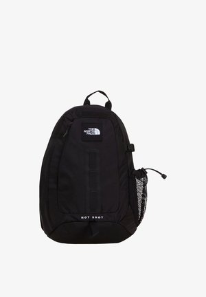 Μαύρο σακίδιο North Face Hot Shot με εμπρόσθια τσέπη με φερμουάρ, πλαϊνή θήκη από δίχτυ για παγούρι και επάνω λαβή μεταφοράς σε λευκό φόντο.