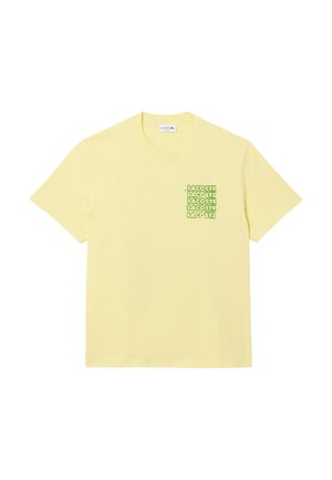 T-shirt en coton jaune avec un petit imprimé graphique vert du mot "LACOSTE" sur la zone du cœur gauche. Manches courtes et col rond.