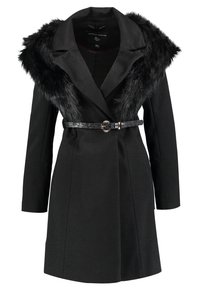 Svart kappa med en krage av kunstpäls, strukturerad design, långa ärmar, midja med bälte och rund metallspänne samt en texturerad tyg.