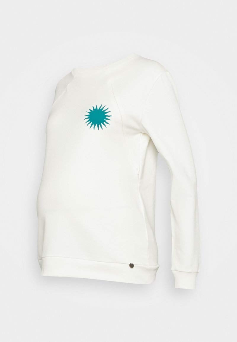 Sweat-shirt de maternité blanc avec un graphisme en forme de rayon de soleil teal sur la poitrine. Il présente des manches longues, un tissu doux et un petit accent marron au niveau de l'ourlet.