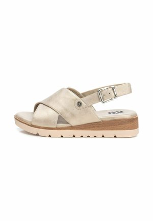 Sandal de cuero beige con correas entrelazadas, hebilla ajustable y una suela de plataforma ligera con un acento de aspecto madera y un dibujo texturizado.