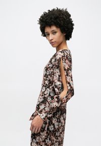 Φόρεμα με λουλουδάτο μοτίβο σε αποχρώσεις του μαύρου, λευκού και ροζ; διαθέτει μανίκια με ανοίγματα, μακριά μανσέτα και χαλαρή εφαρμογή. Υφή υφάσματος λεία.