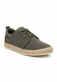 Zapatillas de lona verdes con suela de cuerda natural, acentos en cuero marrón contrastante y cordones redondos. Punta redondeada y diseño de perfil bajo.