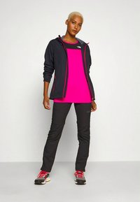 Svart zip-up jacka med rosa detaljer, ljusrosa skjorta, svarta byxor och röda skor. Outfiten har en sportig design och en avslappnad passform.