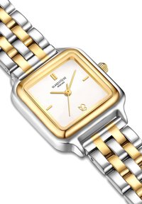 Kuld- ja hõbetoonides ruudukujuline kell valge näoga, kolm kuldset kella käe, ning tekstureeritud metallist pael, kus vahelduvad kuld- ja hõbe lingid.