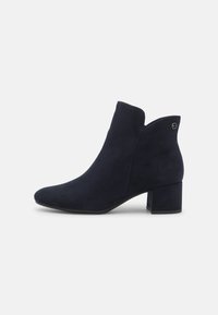 Marineblaues Wildleder-Ankle-Boot mit spitzer Zehe, mittelhohem Blockabsatz und Ausschnitt-Design an den Seiten. Saubere, glatte Textur.