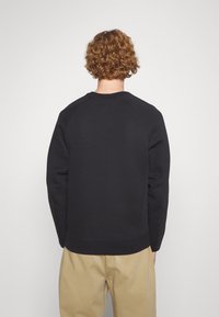 Svart sweatshirt med ribbad rundhals och raglanärmar. Har en jämn textur och en avslappnad passform. Enkelt design, utan mönster eller detaljer.