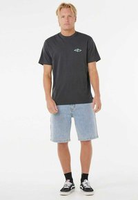 Grijze katoenen t-shirt met een klein turquoise logo op de borst, in combinatie met lichtblauwe denim shorts en zwarte sneakers met witte accenten.